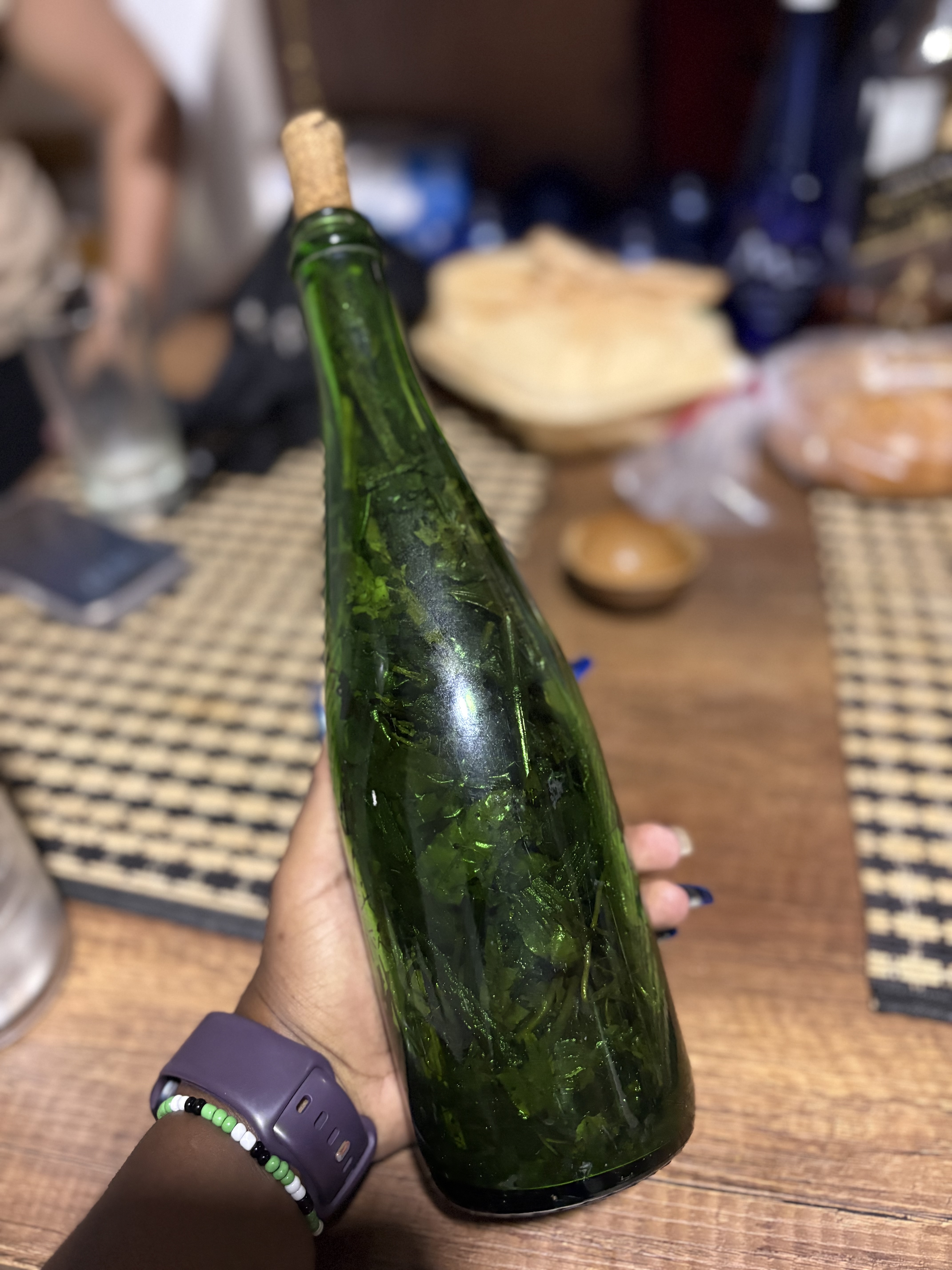 A bottle of viche curao infused with herbs, held at a communal table